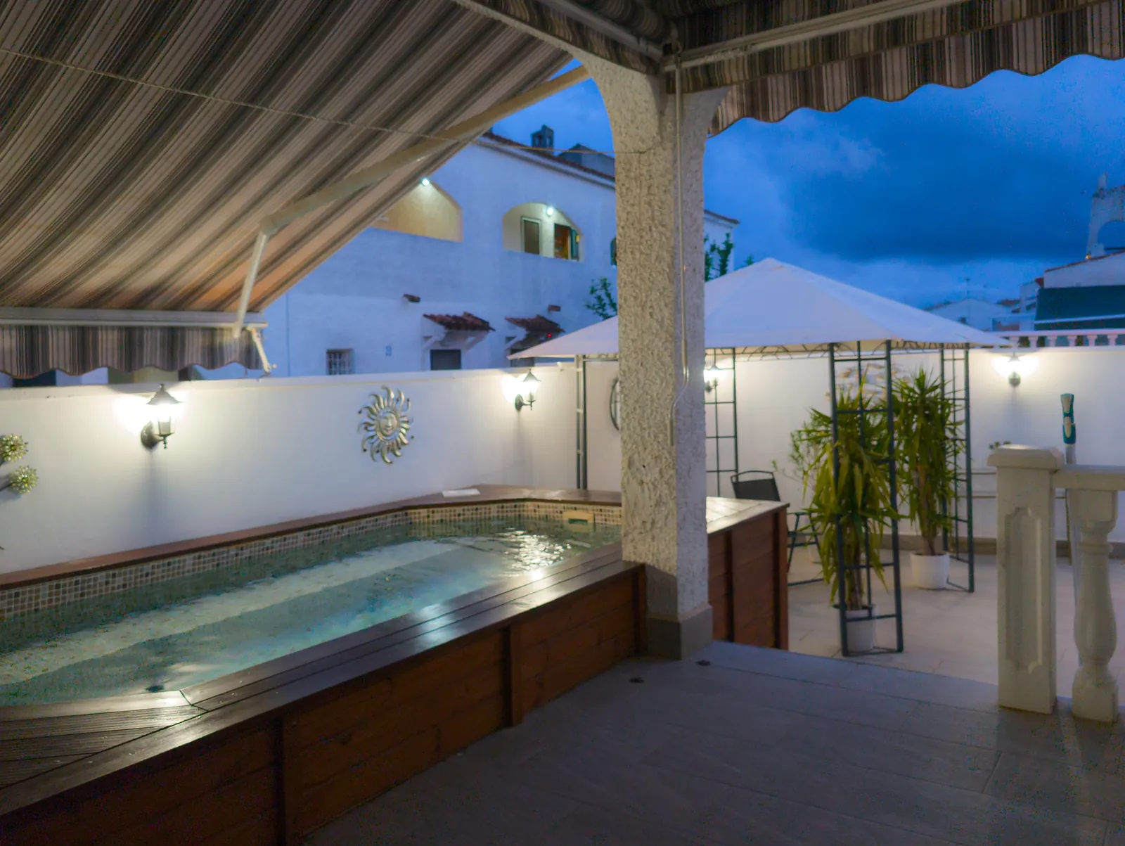 Pool and courtyard lit at dusk, seen from under the awning
